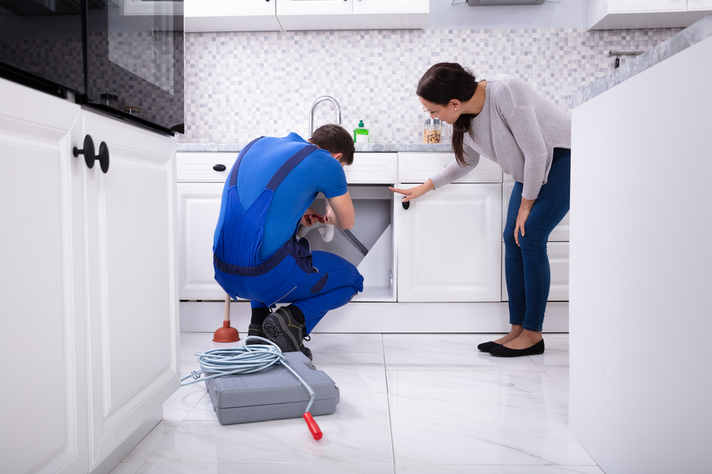 Woman Complaining Clog Sink To Daly City Plumber In Kitchen