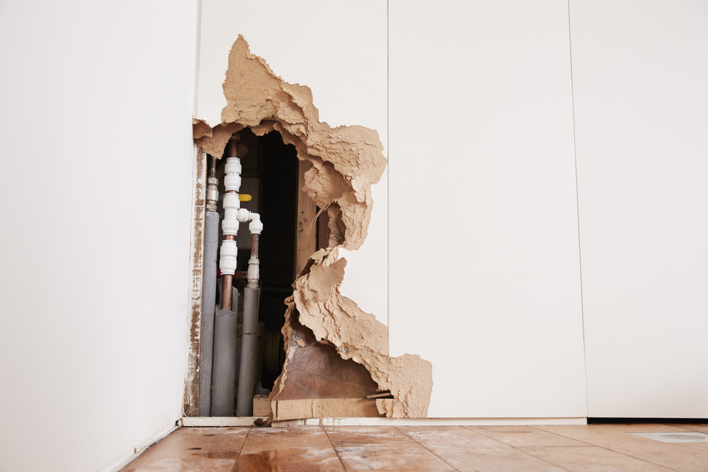 Damaged wall exposing burst water pipes after flood in san francisco
